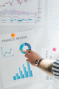 Hand pointing at a financial chart on a wall, illustrating data analysis and review.