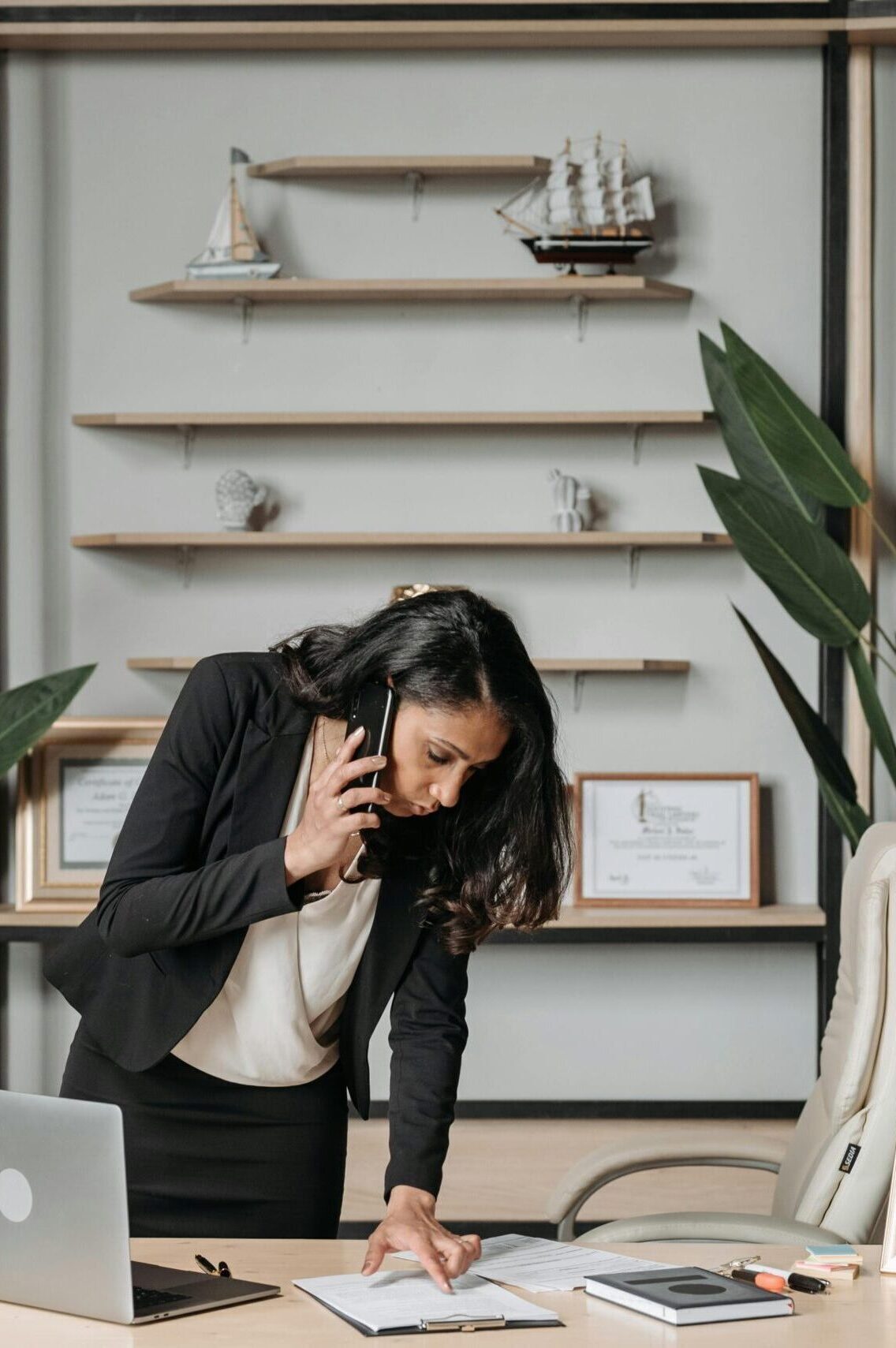 A professional woman lawyer multitasking in a modern office environment, reviewing documents.