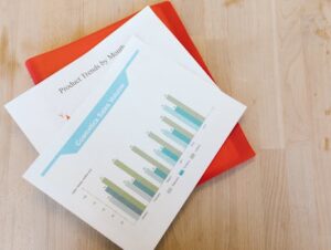 Top view of a cosmetics sales volume report with charts on a wooden desk.